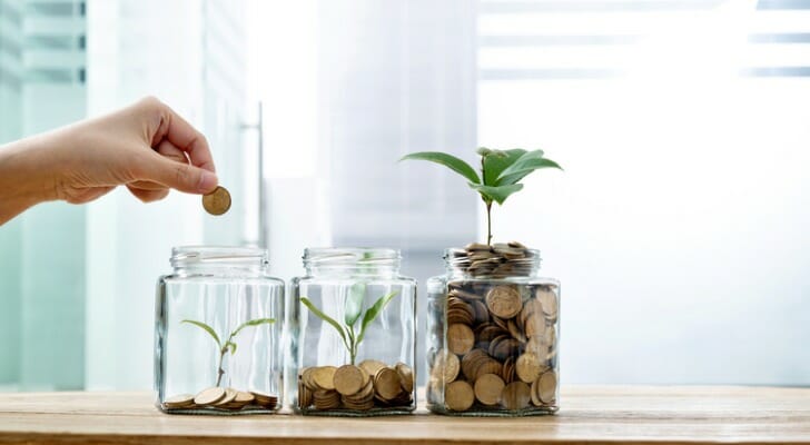 A person putting coins into jars.