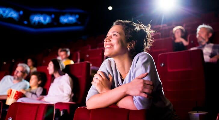 A woman enjoying a film at a movie theater with other viewers.