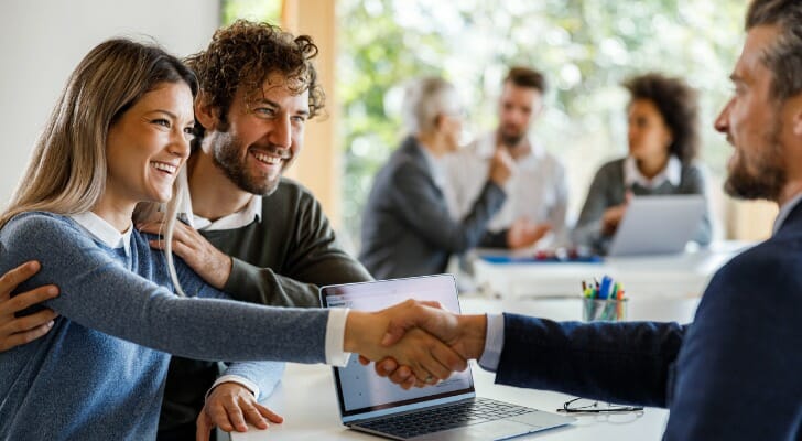 A couple shake hands with a financial advisor.