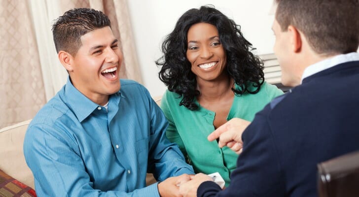 A couple comparing money market and checking accounts with a financial advisor.