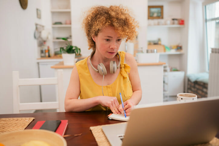 A woman fills out a check, reviewing whether she can write a postdated check.