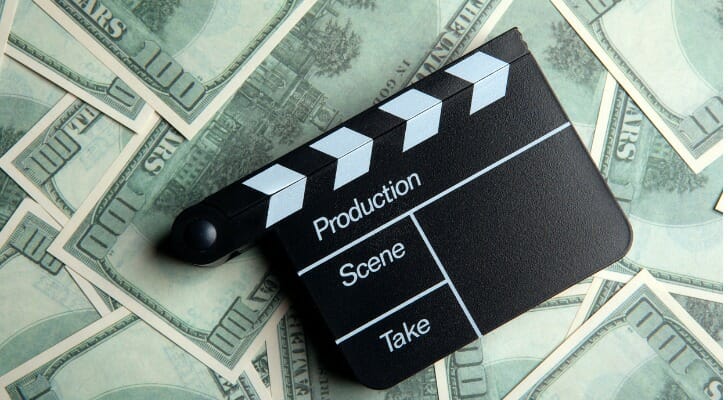 Image of a clapboard, which marks scenes and takes at a movie set, on top of $100 bills.