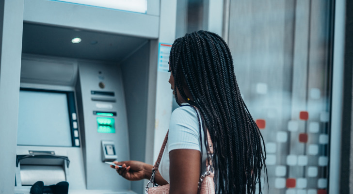 A woman inserting her card into an ATM.