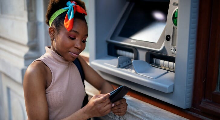A woman removing a card from her wallet to use an ATM.