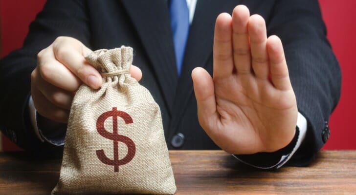 A man with a bag of money, holding up his hand to say "no."