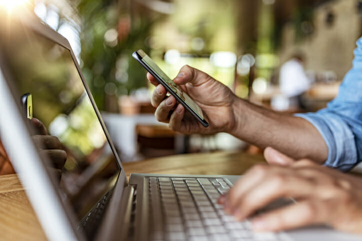 A man using his laptop and his phone.