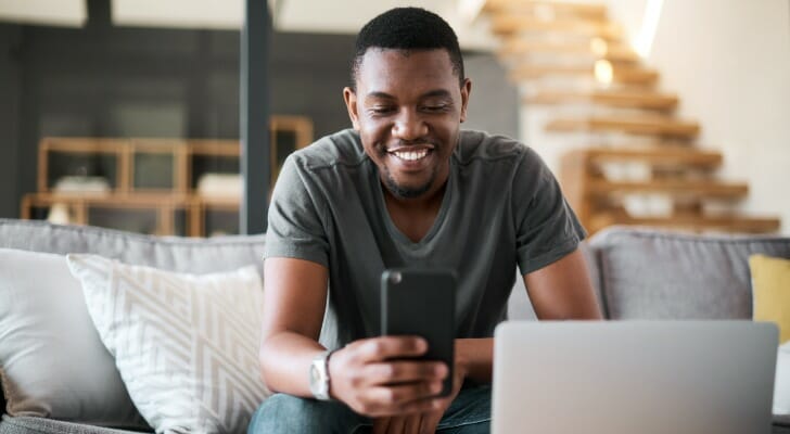 A man reads reviews for Stash vs. Acorns vs. Robinhood.