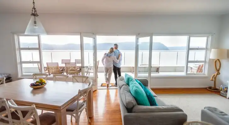 A retired couple look out from the terrace of their lakefront home.