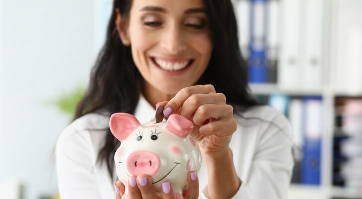 A woman putting change in a piggy bank.