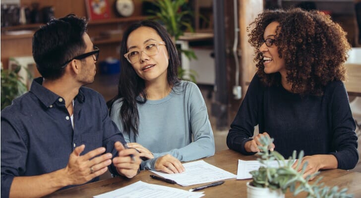 Three friends discuss how to jointly own a residence.
