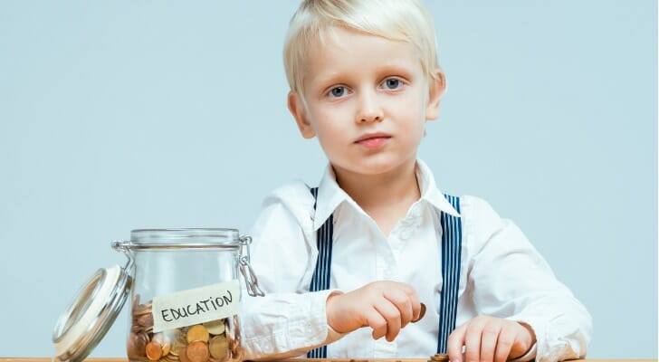 A boy sitting next to a glass jar labeled "Education," representing how saving for college is a long-term goal.
