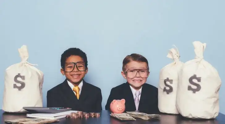 Two children sitting with stacks of money.