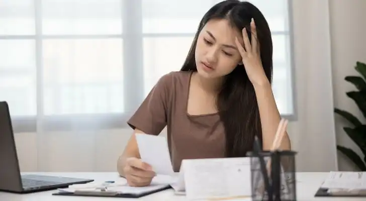 A woman deciding to sign over a third-party check.