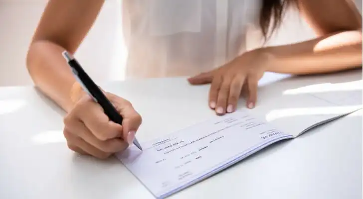 A woman signing a third-party check.