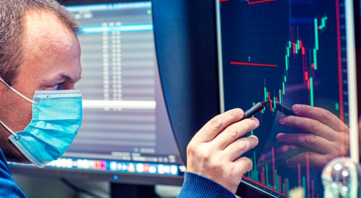 A stockbroker wearing a mask monitors the market during the COVID-19 pandemic.