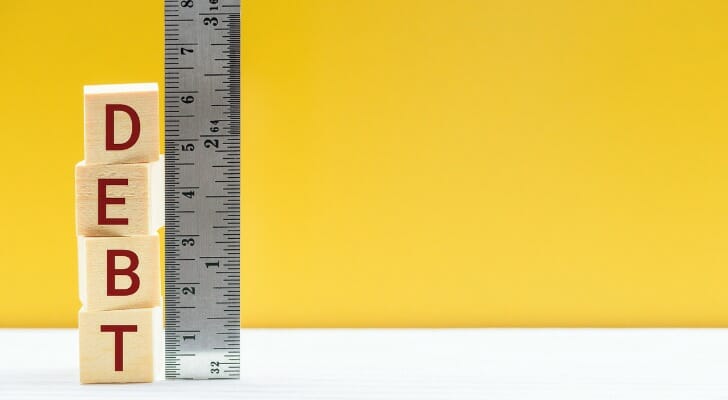 Ruler next to "DEBT" spelled with wooden blocks