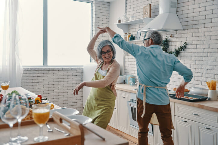 A couple dancing in their kitchen, enjoying retirement at 65 with $4 million.