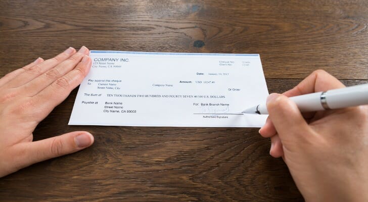 Closeup of a person signing a third-party check.