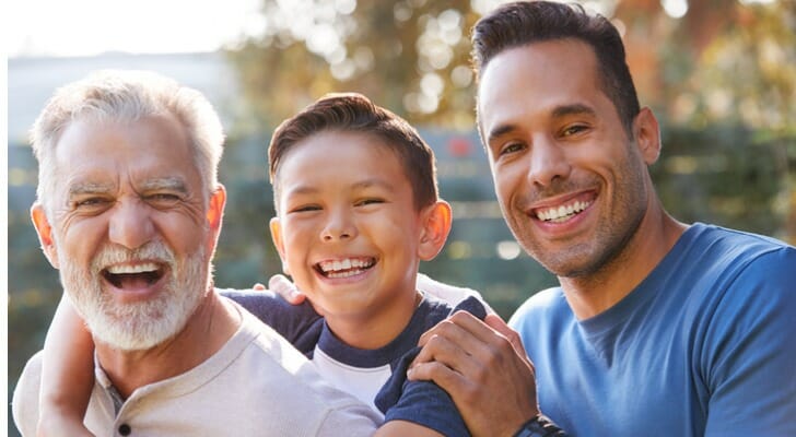 portrait-of-multi-generation-male-hispanic-family-in-garden-smiling-at-camera-SmartAsset-Sandwich-Generation