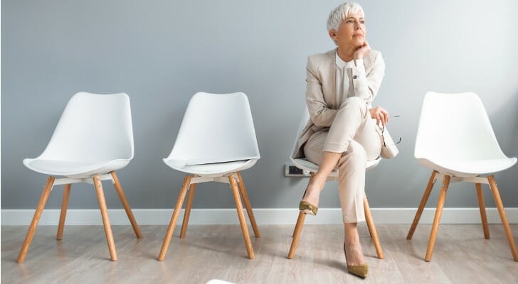 A woman sits on a chair and wonders if you can collect unemployment and Social Security.
