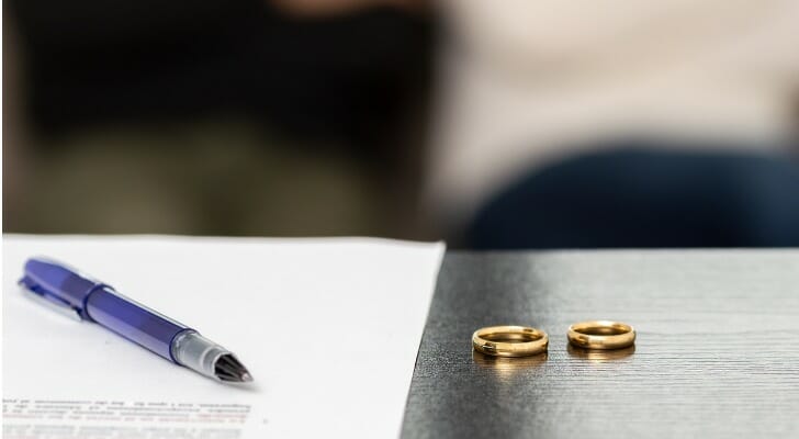 Divorce paperwork and wedding bands on a desk.