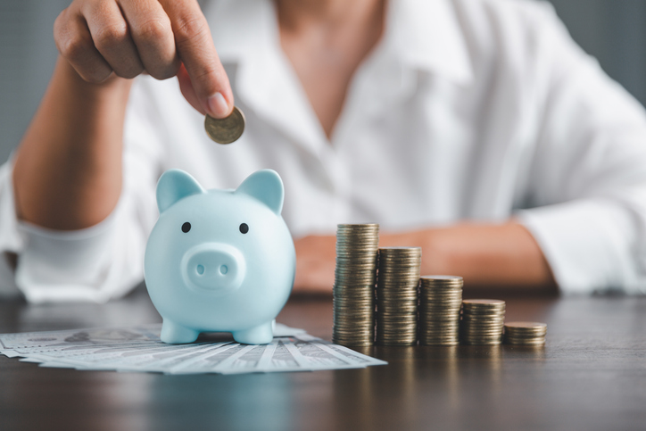 Closeup of a person putting money into a piggy bank.