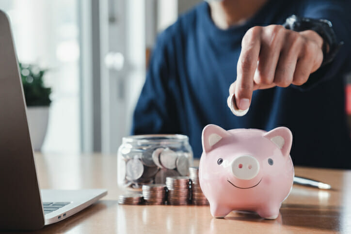 A man putting coins in a piggy bank.