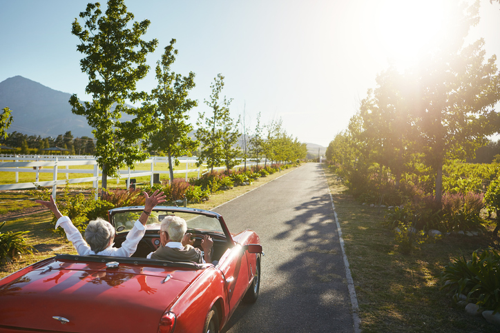 A couple driving a sports car through the country, enjoying their retirement at 55 with $6 million.