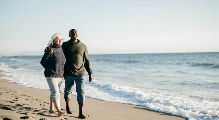 A couple walking on the beach, enjoying their retirement at 55 with $1 million.