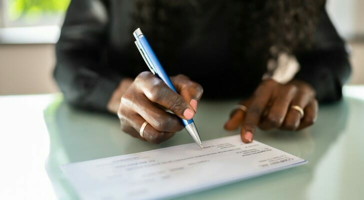 A woman signing a check for her bank account.