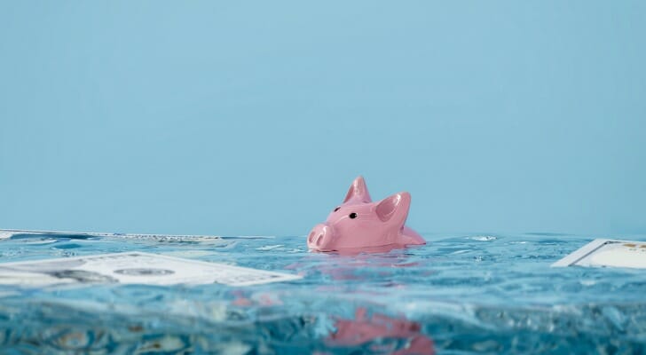 A piggy bank sinking in a pool of water.