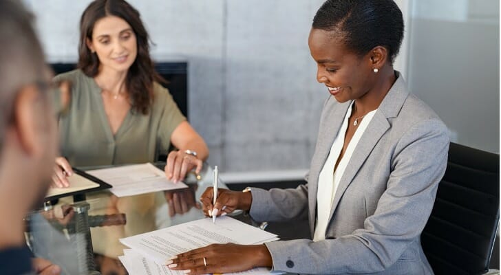 A woman fills out paperwork specifying who inherits if a beneficiary dies.