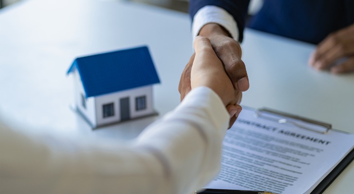 Two real estate investors share hands after agreeing to a deal.
