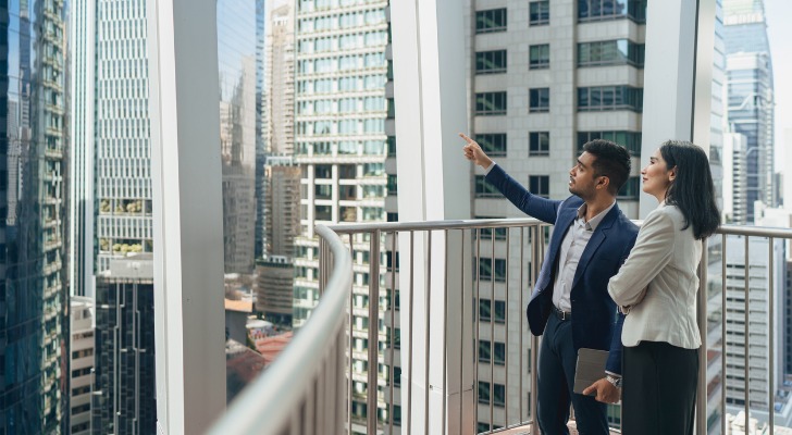 Two people look at a building in which they have invested