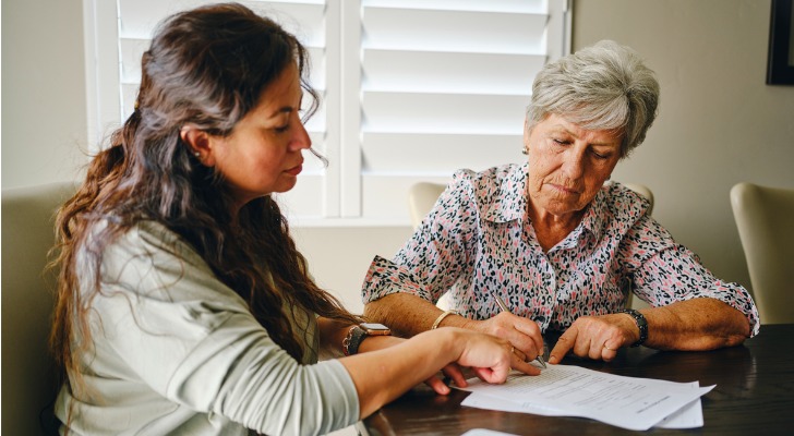 A woman signs some estate plan paperwork in front her daughter.