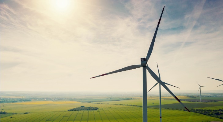 Wind turbines spin above vast fields.