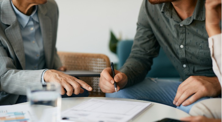 A couple signs paperwork to purchase a dividend-paying whole life insurance policy.