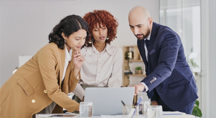 Three people looking at financial accounting statements.
