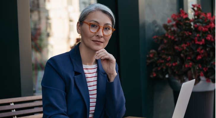 A contrarian investor ponders her next investment move while sitting outside with her laptop.