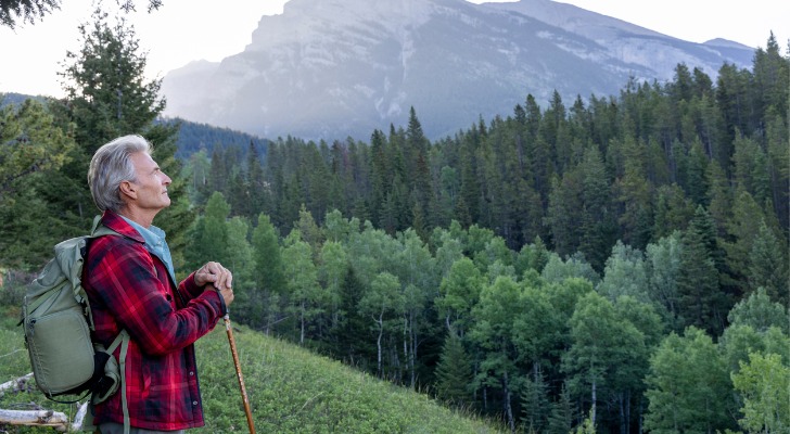 A retiree takes a break during a hike in the mountains.