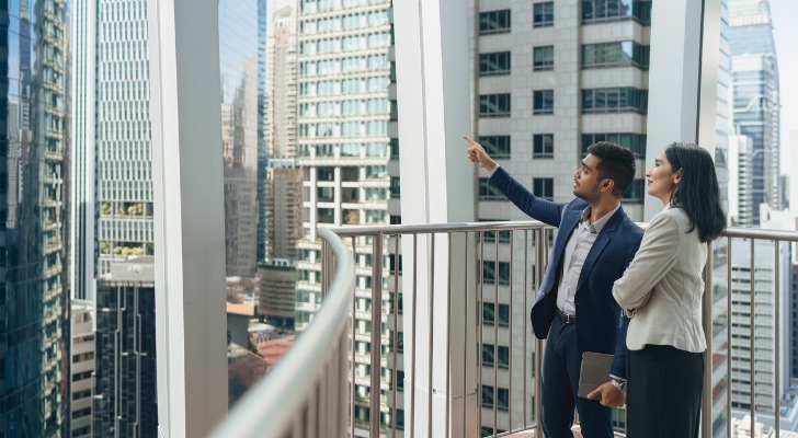 A pair of prospective real estate investors examine surrounding apartment buildings.