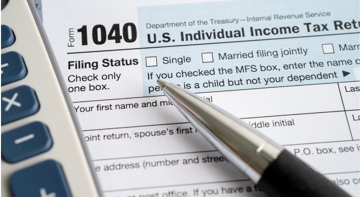 A pen and a calculator sit on top of a 1040 tax form.