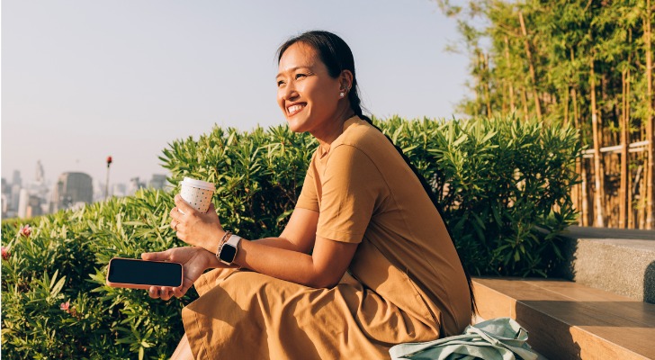 A newly retired woman drinks a coffee while she enjoys the view of a city.