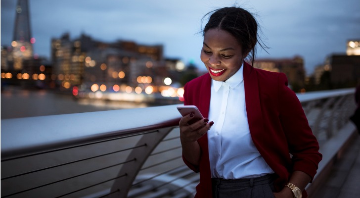 An American expatriate reads an email while walking home from work in London.
