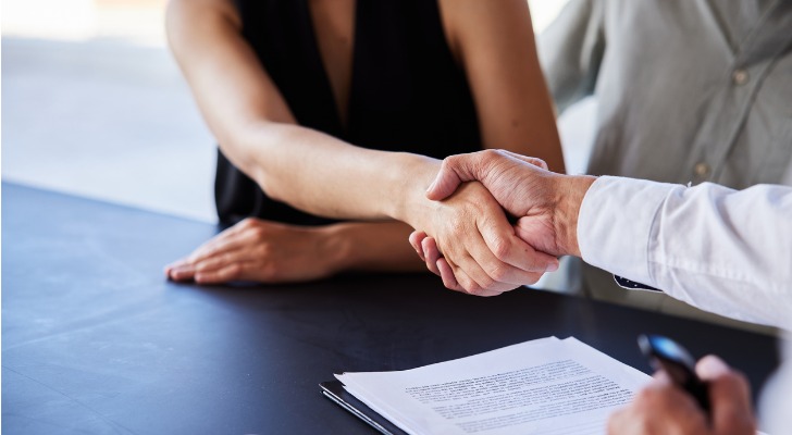 A couple signs mortgage documents to purchase an investment property.