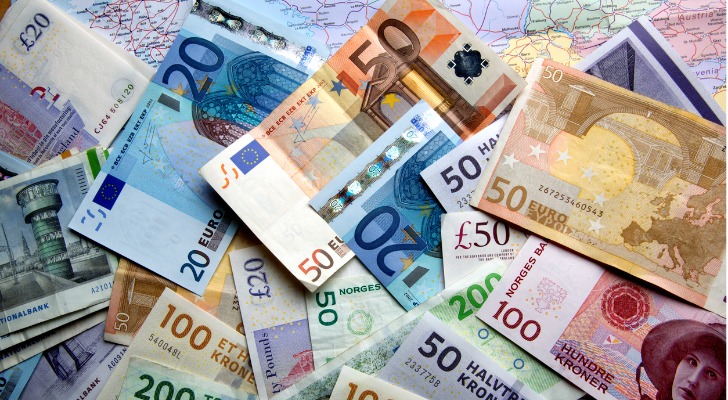 A variety foreign currencies are spread out over a map.