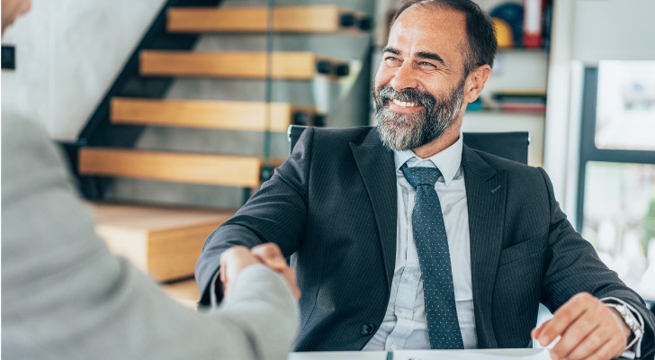 A financial advisor shakes hands with a client at the end of a meeting.