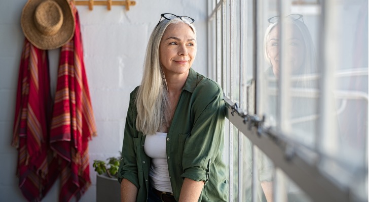 A newly retired woman looks out the window as she thinks about her plans for retirement.
