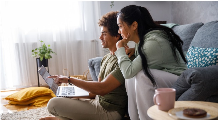 A couple reviews their investment accounts together while sitting in their living room.