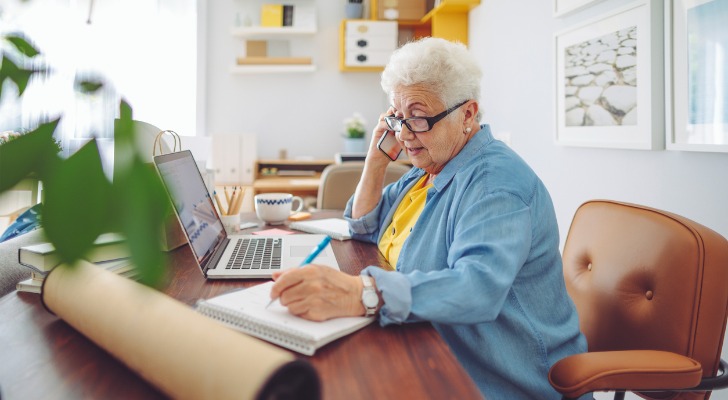 A retiree talks on the phone while working at her part-time job.